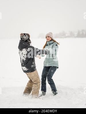 Glückliches Paar tanzt zusammen im Schnee in Winer Stockfoto