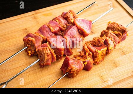 Rohe Pinchos Morunos - Spanish Pork Kebabs: Ungekochte Brocken marinierten Schweinefilet auf Metall-Spieße Stockfoto