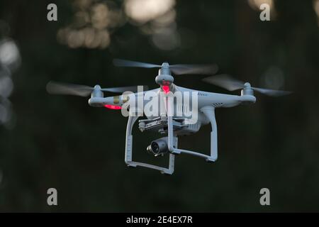 17 - Weiße Quadcopter-Drohne mit roten Lichtern auf dunklem Hintergrund. Unbemannte ariel Fahrzeug mit Kamera Gimbal Nutzlast für die Dreharbeiten Video oder Fotos verwendet Stockfoto