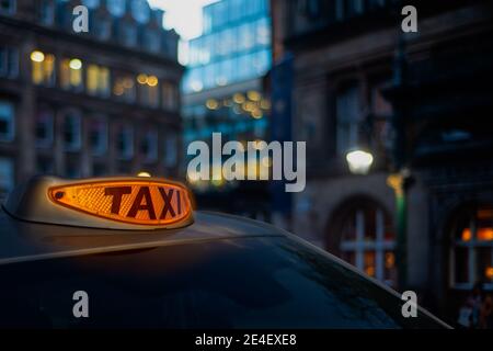 Ein leuchtendes orangefarbenes Taxistand in EINER Londoner Straße Dämmerung Stockfoto