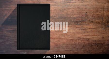 Buch leerer Deckel auf Holztisch Hintergrund. Geschlossene schwarze Buchvorlage, Platz zum Kopieren. 3d-Illustration Stockfoto
