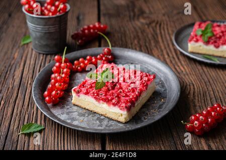 Süßes Dessert mit roten Johannisbeeren gefüllt mit Frischkäse, dekoriert mit frischen Beeren auf Holzhintergrund Stockfoto