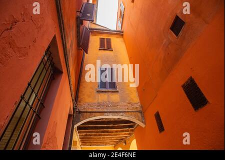 Italienische Fenster an der orangefarbenen Wandfassade mit geschlossenem Braun Farbe schuppige klassische Fensterläden Stockfoto