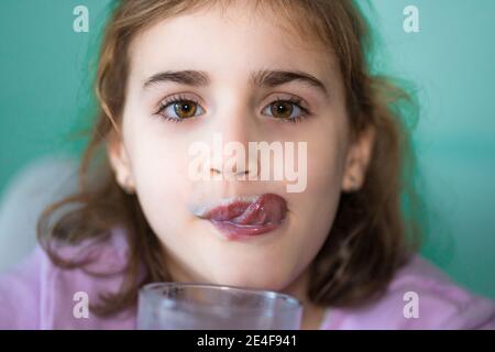 Mädchen schmeckt Milchglas und leckt ihre Lippen, gesunde Ernährung Konzept, Nahaufnahme Porträt, selektive Fokus Stockfoto