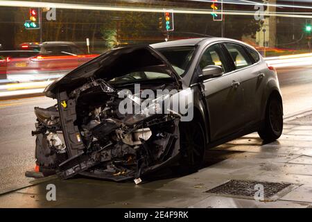 Schwer beschädigtes Auto, das nachts am Straßenrand in London aufgegeben wurde Straße Stockfoto