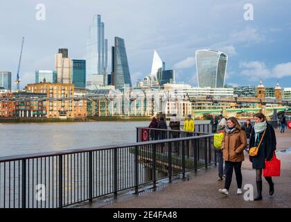 London-Leute, die an einem Wintertag in London, Großbritannien, am South Bank River Path oder Southbank entlang der Themse mit Blick über die City of London spazieren Stockfoto