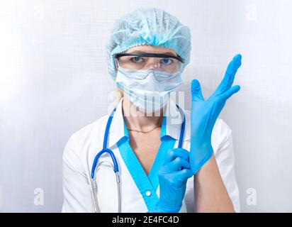 Krankenschwester in Schutzkleidung legt Gummihandschuhe, persönliche Schutzausrüstung im Kampf gegen Krankheiten Stockfoto