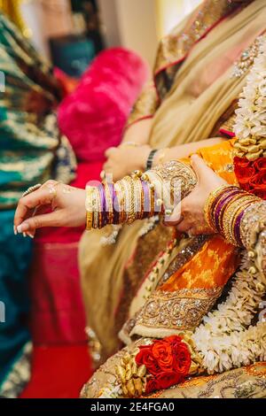 Nahaufnahme indischen pakistanischen Braut Hände mit goldenen Henna in Gelbes Kleid tragen viele Schmuck Armbänder während mehndi Hochzeitsfeier Stockfoto