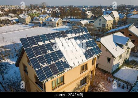 Hausdach mit Solarpaneelen im Winter mit Schnee bedeckt. Energie-Effizienz- und Wartungskonzept. Stockfoto