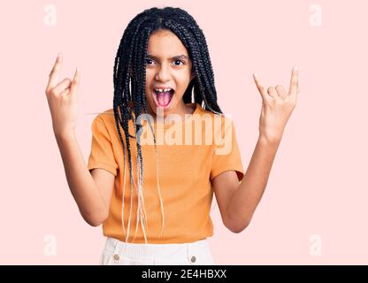 Cute african american Mädchen tragen lässige Kleidung schreien mit verrückten Ausdruck tun Rock-Symbol mit Händen nach oben. Music Star. Heavy Konzept. Stockfoto