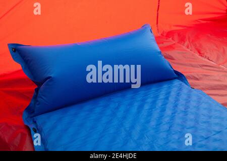 Ein blaues selbstaufblasendes Blow-up Matratzenpolster wird eingelegt Ein rotes Zelt für einen komfortablen Schlaf für Camper Oder diejenigen mit einem schlechten Rücken Stockfoto