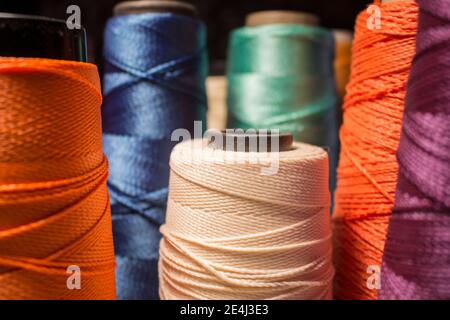 Mehrere farbige Spulen und Linienkegel. Blaue, orange violette, grüne, weiße Fäden. Stockfoto