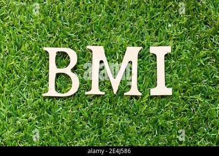 Buchstabe im Wort BMI (Abkürzung für Body Mass Index) Auf grünem Gras Hintergrund Stockfoto