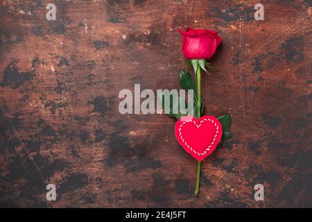 Valentinstags-Grußkarte mit roter Rose und dekorativem Textilherz auf Holzhintergrund. Draufsicht. Kopierbereich - Bild Stockfoto