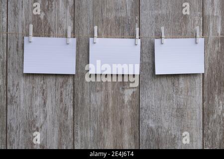 Leere Bilderrahmen hängen an der Wäscheleine. Isoliert auf Holzhintergrund. Vintage-Style. Leere Papierstücke hängen an der Wäscheleine. Speicherplatz kopieren Stockfoto