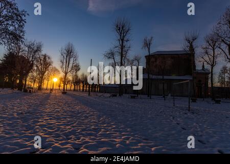 Die Sonne geht über der schneebedeckten Ebene und dem Heiligtum von Varallino di Galliate, Novara, Piemont, Italien Stockfoto