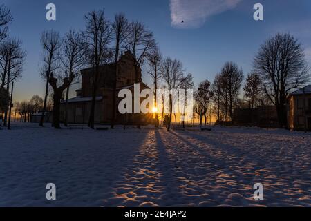 Die Sonne geht über der schneebedeckten Ebene und dem Heiligtum von Varallino di Galliate, Novara, Piemont, Italien Stockfoto
