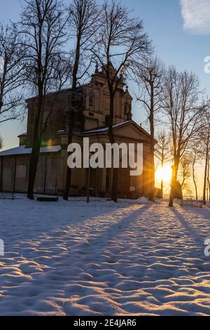Die Sonne geht über der schneebedeckten Ebene und dem Heiligtum von Varallino di Galliate, Novara, Piemont, Italien Stockfoto