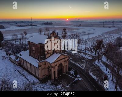 Die Sonne geht über der schneebedeckten Ebene und dem Heiligtum von Varallino di Galliate, Novara, Piemont, Italien Stockfoto