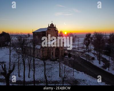 Die Sonne geht über der schneebedeckten Ebene und dem Heiligtum von Varallino di Galliate, Novara, Piemont, Italien Stockfoto
