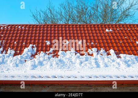 Schnee schmilzt vom Dach des Hauses an einem Frühlingstag. Lawinengefahr von Dächern. Schneeräumung. Stockfoto