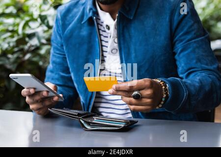 Nahaufnahme des Mannes mit Kreditkarte, die mobile Zahlung an Straßencafé Stockfoto