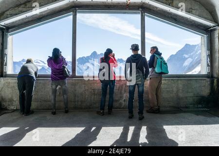 Passagiere mit Blick aus dem Fenster am Bahnhof Eismeer auf der Jungfraubahn im Berner Oberland, Schweiz Stockfoto