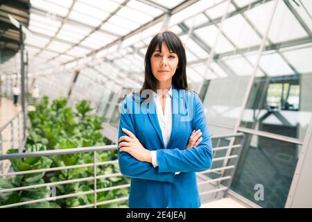 Elegante Unternehmerin mit Armen im Korridor des Büros gekreuzt Stockfoto