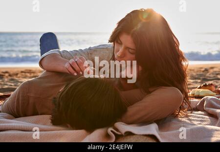 Junge Frau, die sich mit dem Mann am Strand ausruhte Stockfoto