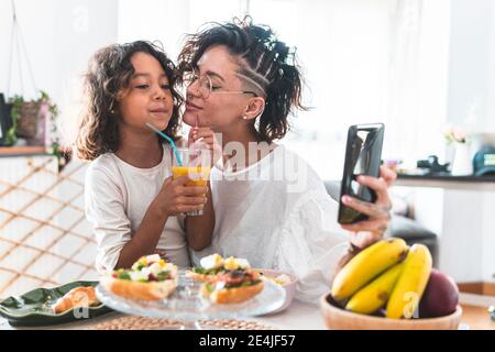 Mutter und Tochter nehmen Selfie während des Frühstücks Stockfoto