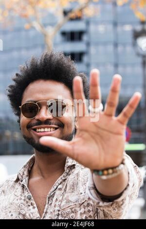 Nahaufnahme eines stylischen Mannes mit Sonnenbrille mit Stop-Geste Stockfoto