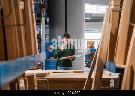Zimmermann steht in der Produktionshalle mit Ringbinder in den Händen Stockfoto