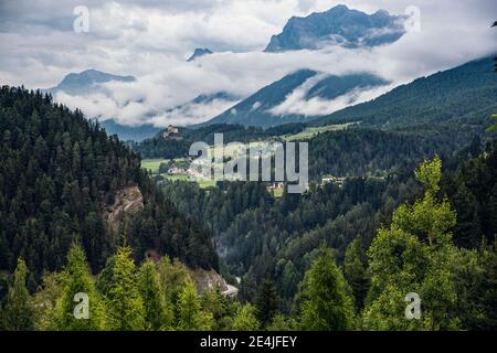 Schweiz, Kanton Graubünden, Scuol, Grünes Waldtal mit Schloss Tarasp im Hintergrund Stockfoto
