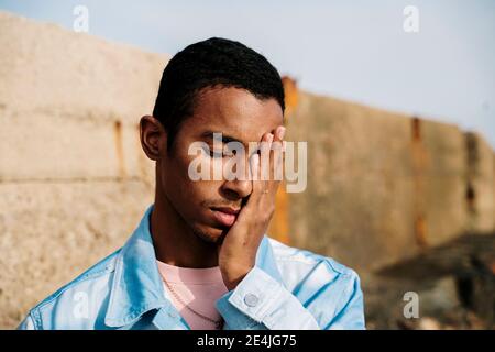 Mann mit Kopf in Händen und geschlossenen Augen im Freien stehend Stockfoto