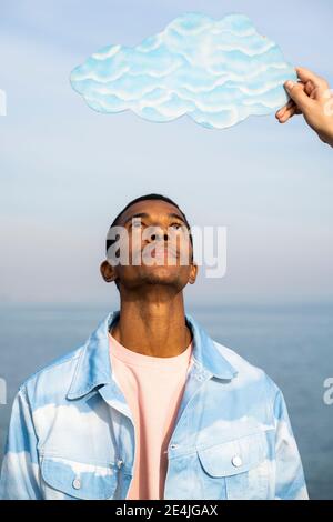 Mann stehend und Blick auf männliche Hand hält Wolke geschnitten Draußen gegen den Himmel Stockfoto