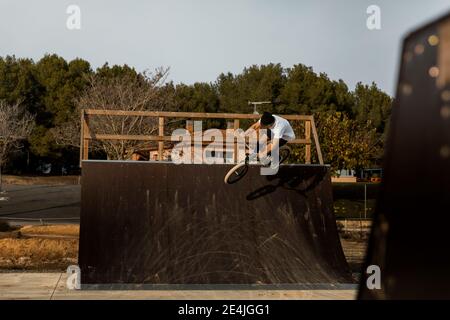 Junger Mann macht Stunt auf Rampe am Bikepark während Sonniger Tag Stockfoto
