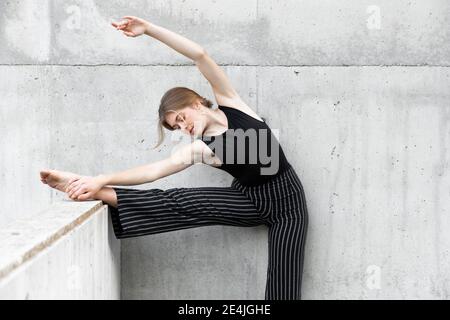 Tänzerin in schwarz gestreiften Hosen vor Beton Wand Stockfoto