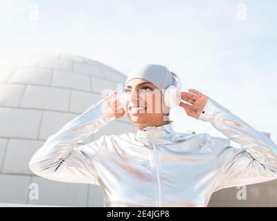 Junge Frau in glänzendem Schutzanzug mit OK-Schild, während sie gegen Iglu steht Stockfoto