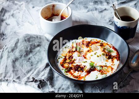 Pochierte Eier Frühstück mit Joghurt und würziger Paprikaputter in Schüssel auf dem Tisch Stockfoto