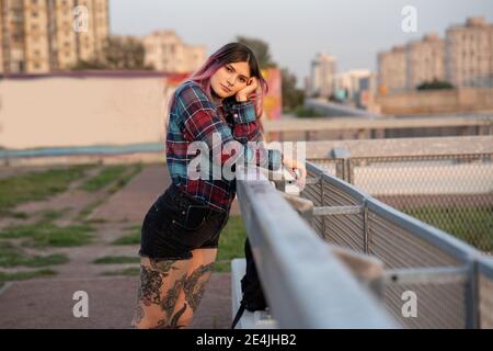 Hipster Weibchen mit rosa Haaren auf Geländer auf dem Dach gelehnt Stockfoto