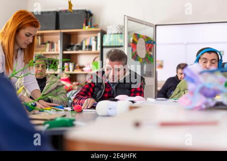 Rotschopf weibliche Betreuer tun kreative Handwerk mit behinderten Menschen und Frau im Pflegeheim Stockfoto