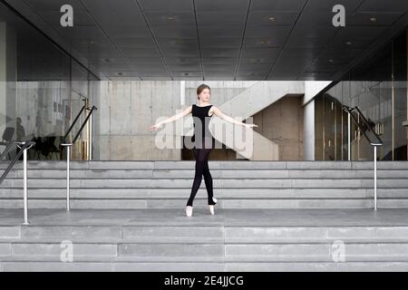 Ballerina in schwarzem Trikot in modernem Betongebäude Stockfoto