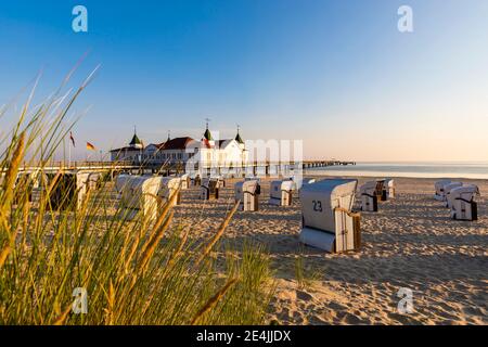 Deutschland, Mecklenburg-Vorpommern, Ahlbeck, Kapuzenliegen am Sandstrand mit Badehaus im Hintergrund Stockfoto