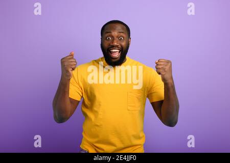 Schwarzer Mann ist glücklich. Freudiger und glücklicher Ausdruck. Violetter Hintergrund Stockfoto