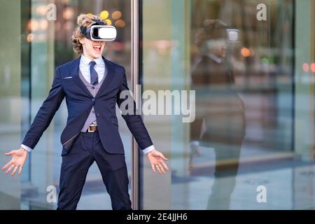 Aufgeregt männlichen Unternehmer schreien, während das Tragen VR-Box gegen das Büro Gebäude Stockfoto