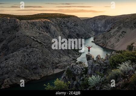 Mann, der auf Felsen steht und auf den Fluss in der Schlucht schaut Bei Sonnenuntergang Stockfoto
