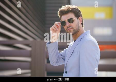 Junger schöner Mann trägt Sonnenbrille im städtischen Hintergrund Stockfoto