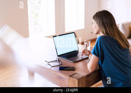 Brunette Geschäftsfrau mit Laptop am Tisch während der Arbeit in zu Hause Büro Stockfoto
