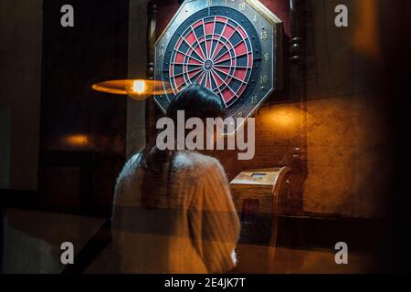 Junge Frau spielt Darts in der Bar Stockfoto