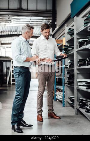 Männliche Inspektoren, die Ausrüstung überprüfen, während sie in der Werkstatt in der Industrie stehen Stockfoto